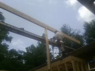 Carpenter setting a ridge beam over a new addition frame — Ice Dam Removal by Roofing Brothers in Copiague