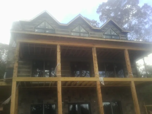 Dormers and porch framing on a large log home under construction — Roof Coating work by our crew in Copiague