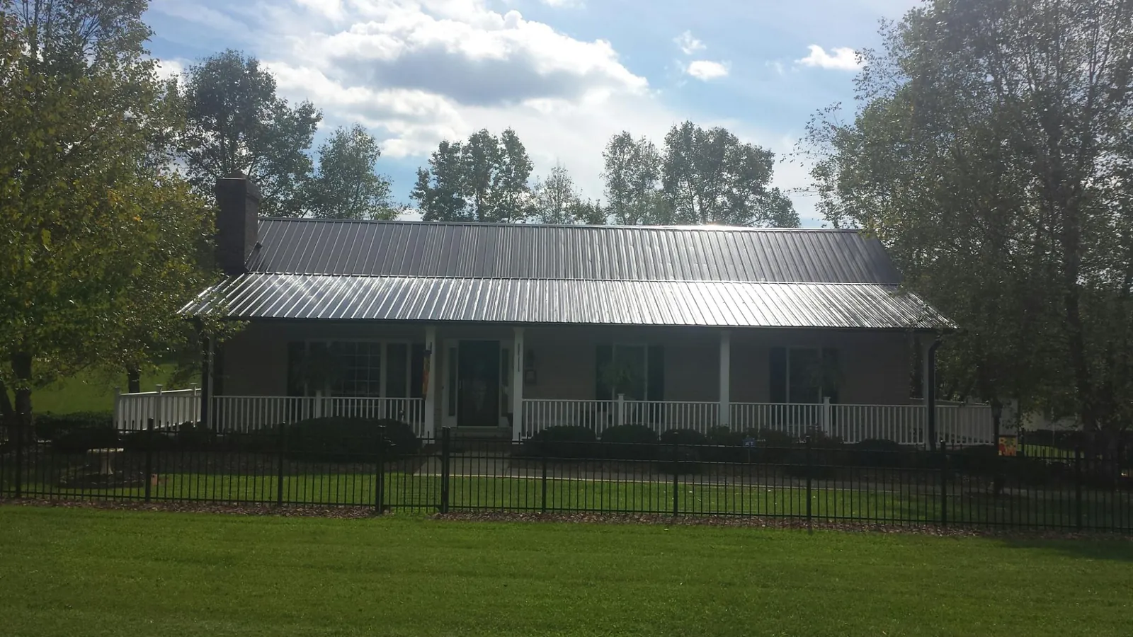 Gray metal roof on a brick ranch with a full width front porch — Gutter Guard Installation work by our crew in Copiague