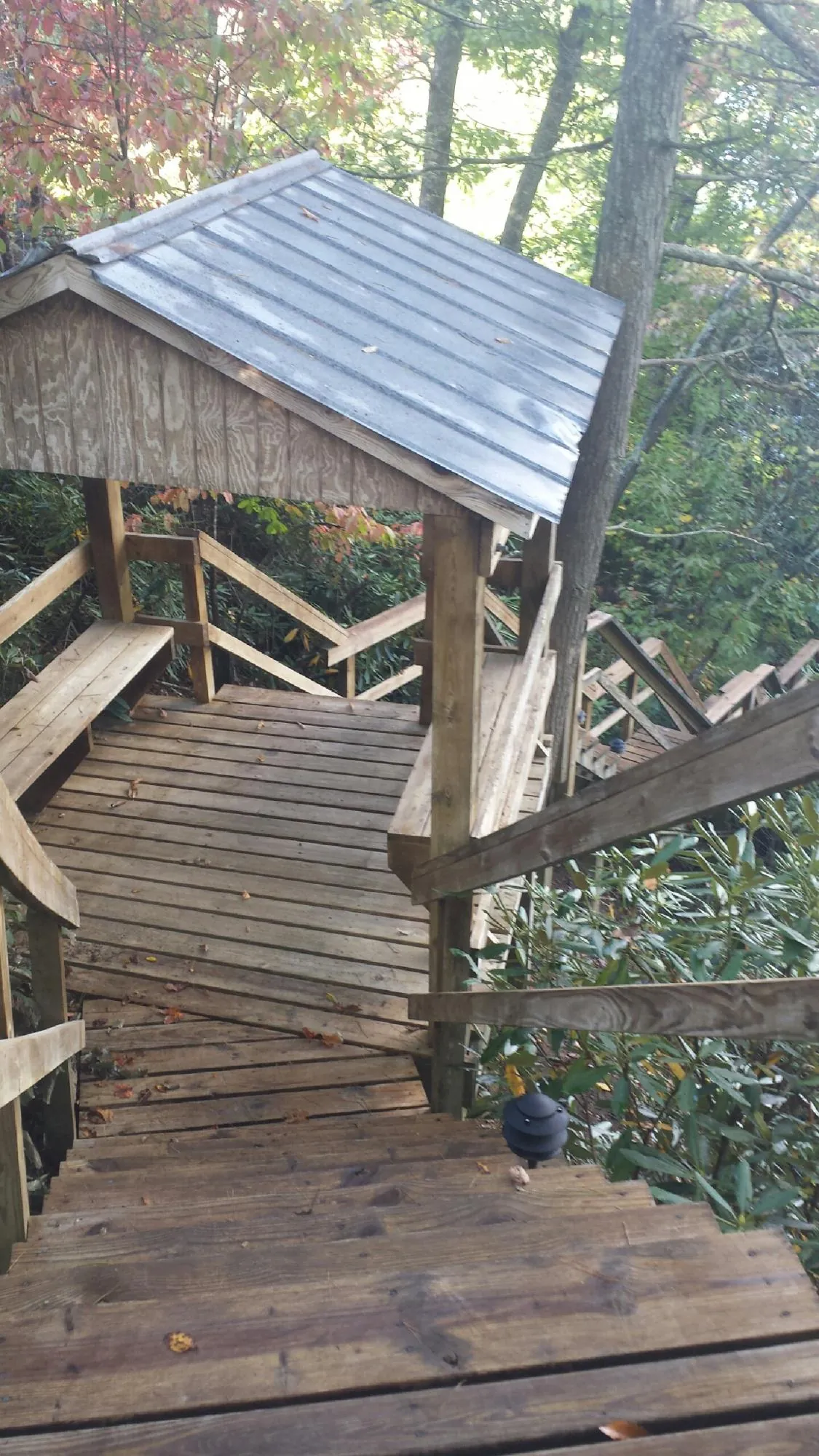 Metal roofed shelter over wooden steps on a wooded walkway — Skylight Repair & Installation work by our crew in Copiague