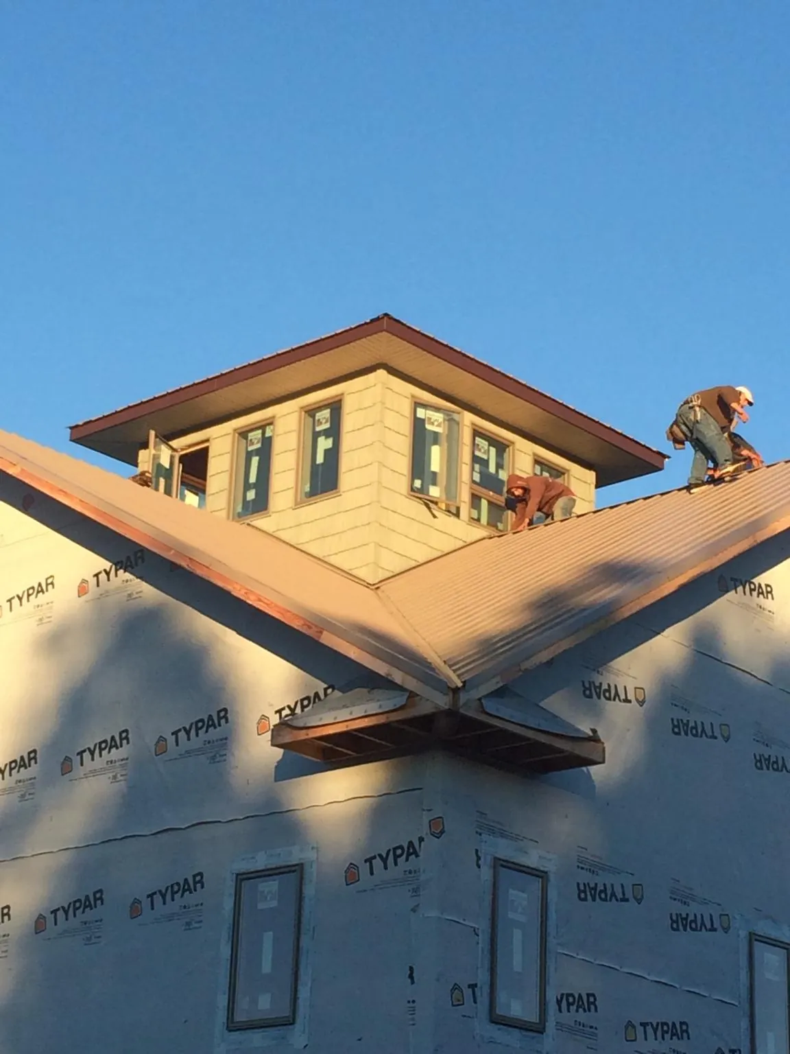 Roofers working around a rooftop cupola on a new metal roof at sunset — Roof Waterproofing in Copiague by Roofing Brothers